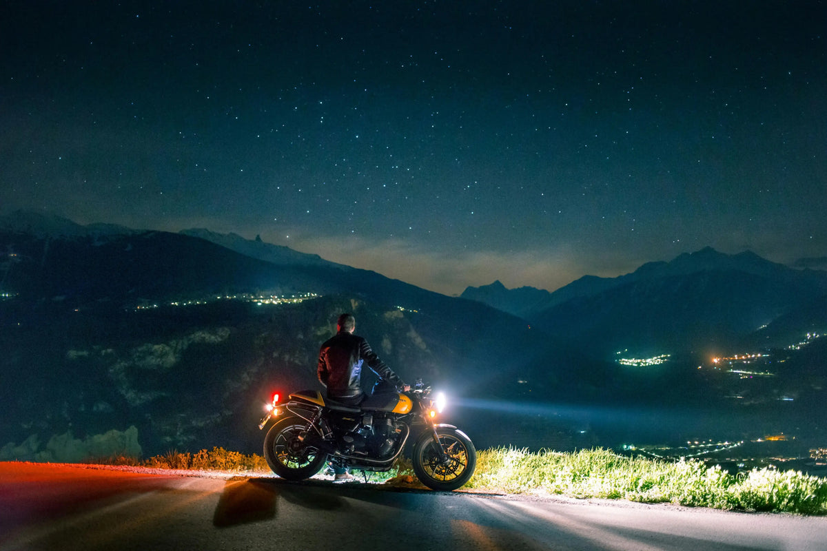 Safe night motorcycle riding on a dark mountain road with active lighting